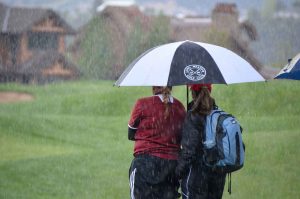 Berthoud’s Molli Boruff and coach Mary Durkin take shelter under an umbrella as the rain comes down on the 14th hole at River Valley Ranch in Carbondale Tuesday during the girls 4A State Golf Championship. The wet and cold weather made for some challenging golf at the state tournament. Colleen O’Neil / Special to The Surveyor